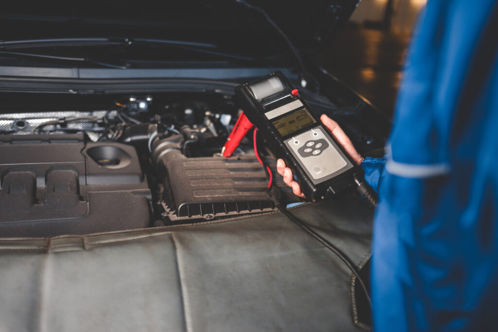 Monteur controleert de accustatus van een auto met een digitale tester bij Dynamostartmotor.nl.