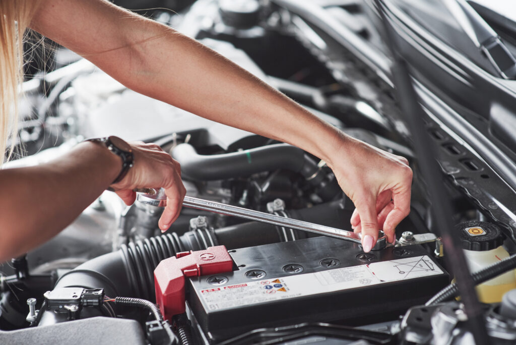 Vrouw vervangt een auto-accu met een momentsleutel, specialistische accudienst bij Dynamostartmotor.nl.